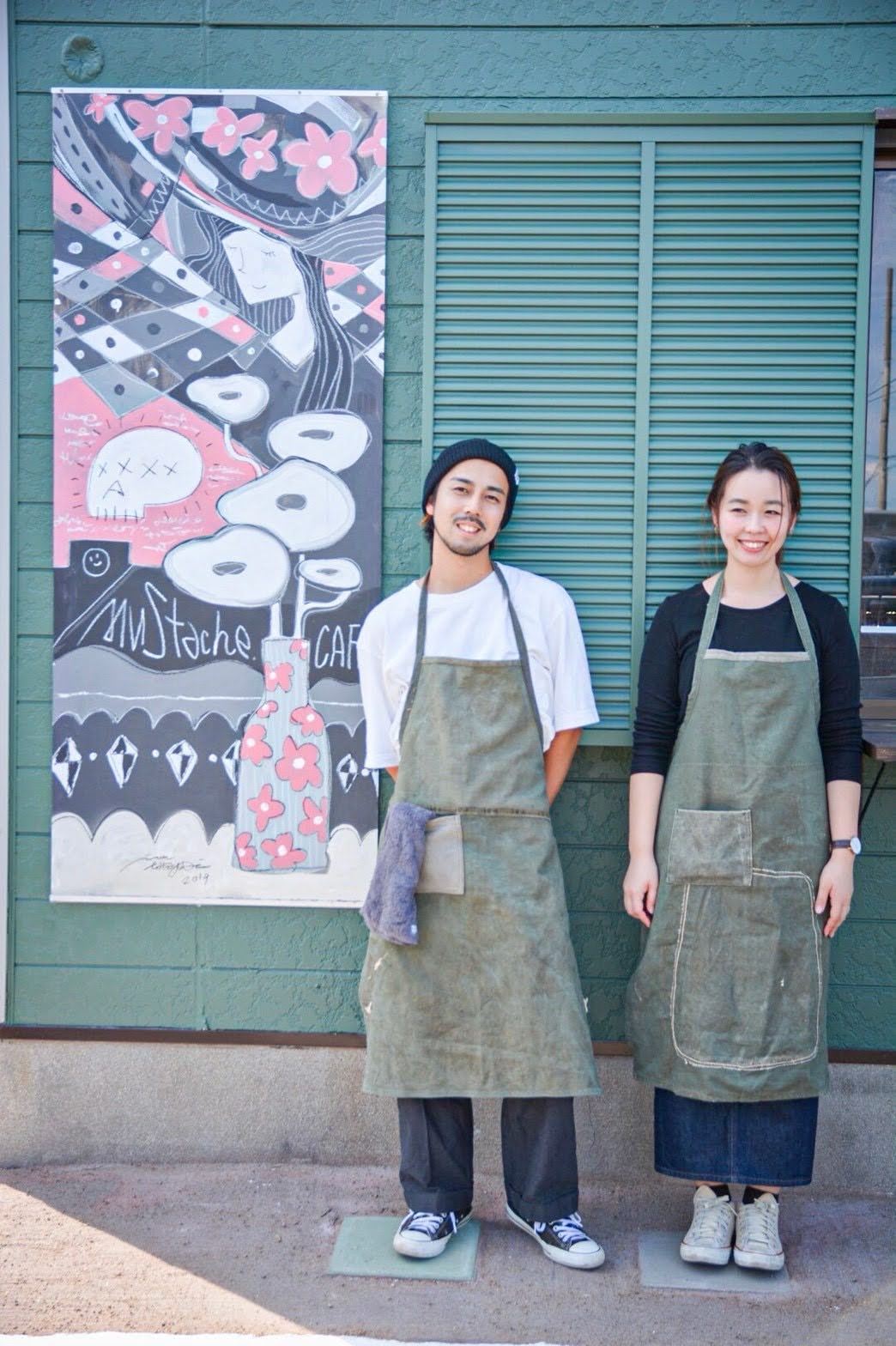 オーナー夫妻 店外の壁画前にて